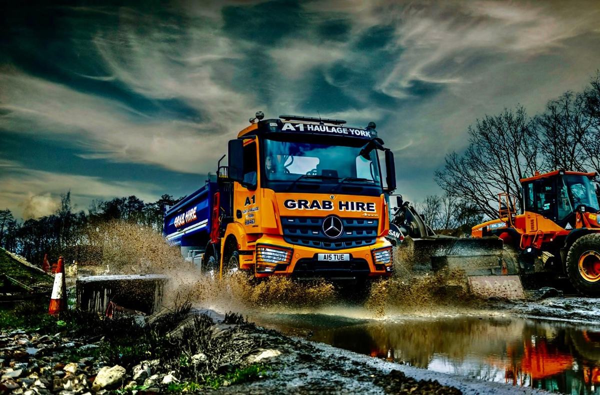 A1 Haulage York grab hire lorry driving through a wet site with a loading shovel behind